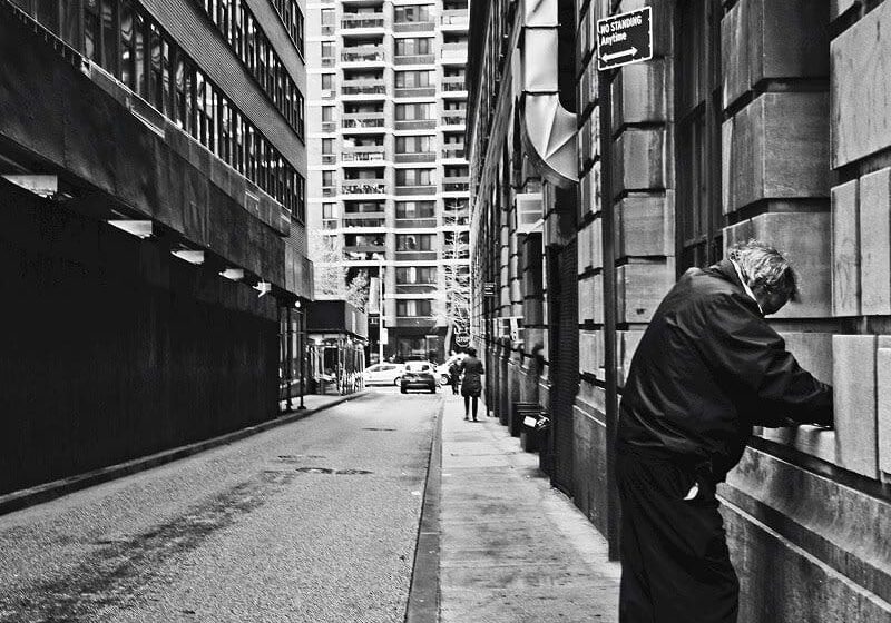Man leaning on wall in city alley.